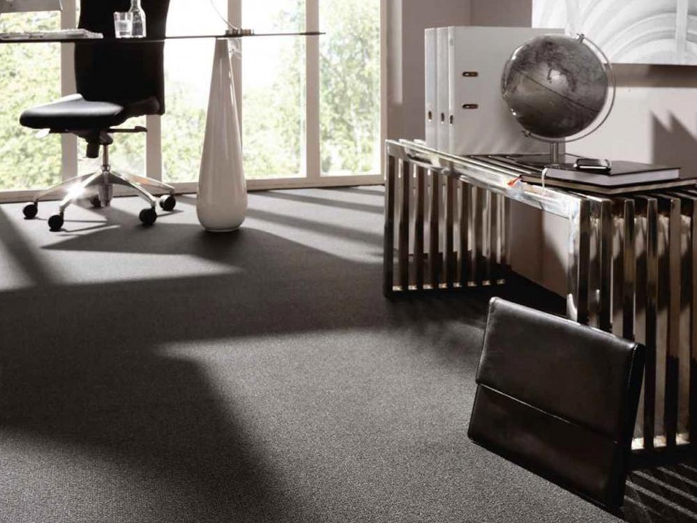 B&uuml;roeinrichtung mit dunkelgrauem Teppichboden, Glas-Schreibtisch, Stuhl und dekorativen Elementen